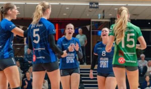 Vrouwelijke volleyballers vieren overwinning tijdens wedstrijd.
